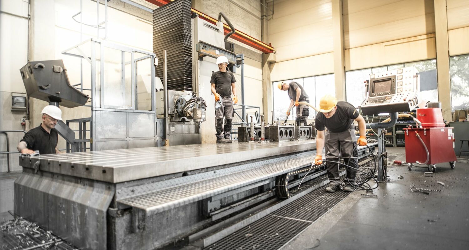 Vier Mitarbeiter bei der Reinigung einer industriellen Maschine
