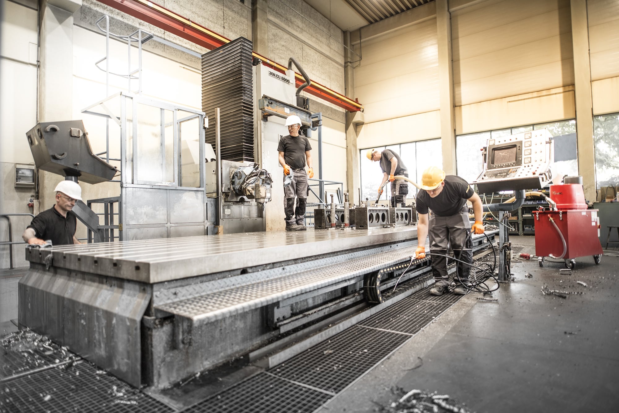 Vier Mitarbeiter bei der Reinigung einer industriellen Maschine